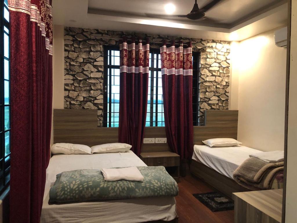 two beds in a room with red curtains at Sakhiya Fish Resort Pvt Ltd in Chhapia