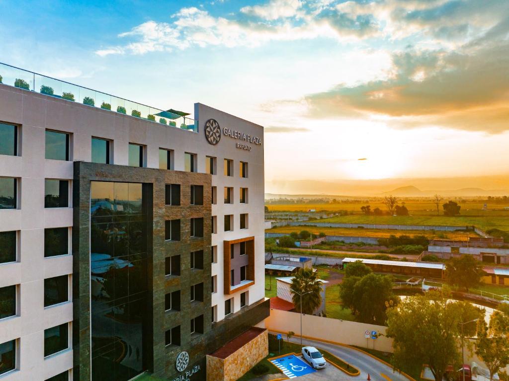 a hotel with the sunset in the background at Galeria Plaza Irapuato in Irapuato