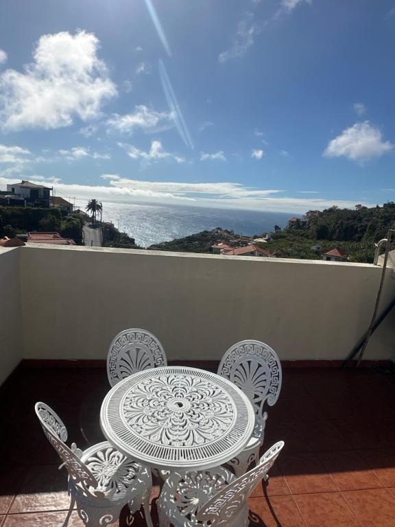 a table and chairs on a balcony with a view of the ocean at Elisabeth House in Ponta do Sol