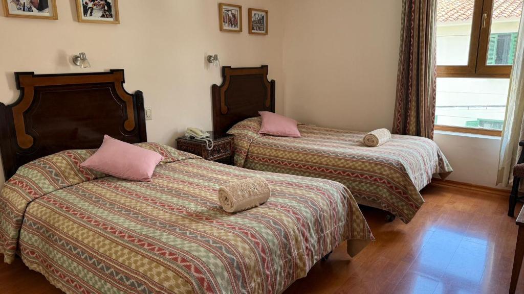 two beds with pink pillows in a room at Casa Elena in Cusco