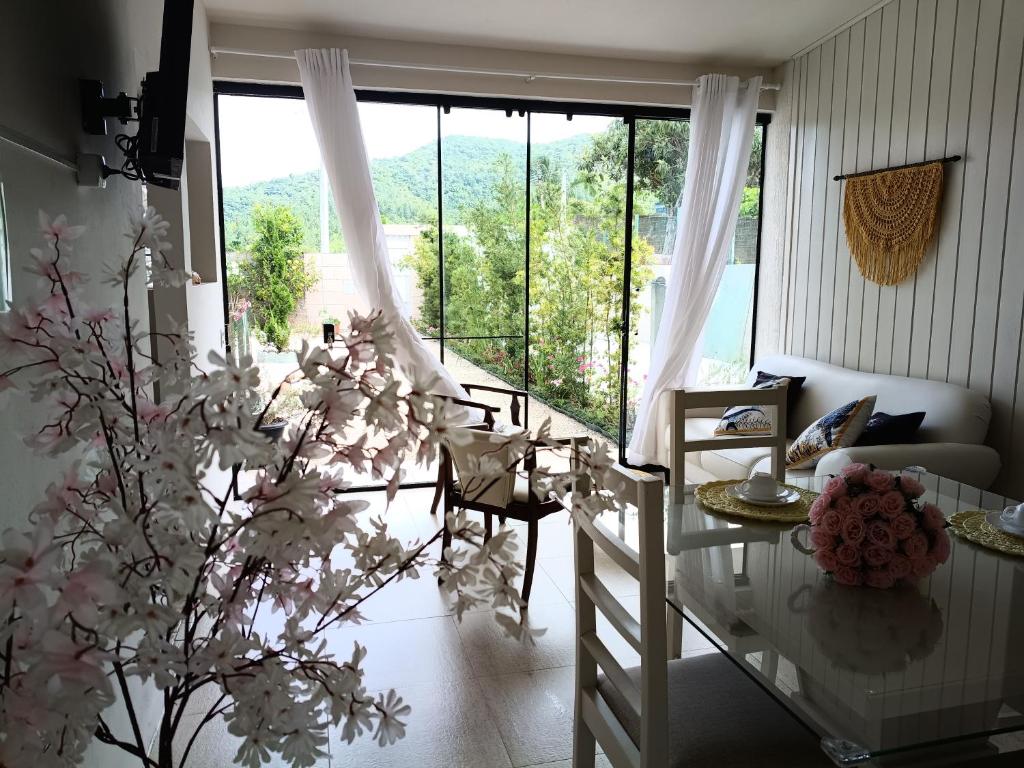 a living room with a table and a large window at Casa MonteFlor - Refúgio onde a vida desacelera com gentileza in Governador Celso Ramos