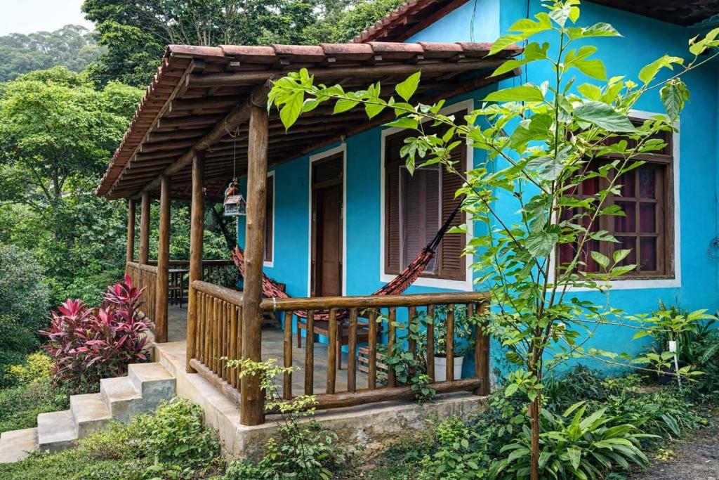 a blue house with a porch and a balcony at Pouso Ravenala - Refúgio do viajante in Paraty