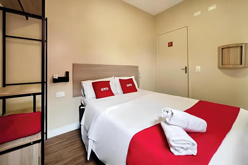 a bedroom with a large white bed with red pillows at OYO Hotel Itarantim, São Paulo in São Paulo