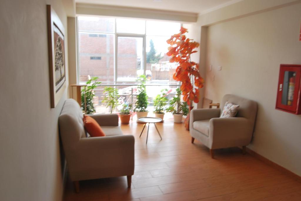 a living room with two chairs and potted plants at Kymeron Hotel in Juliaca