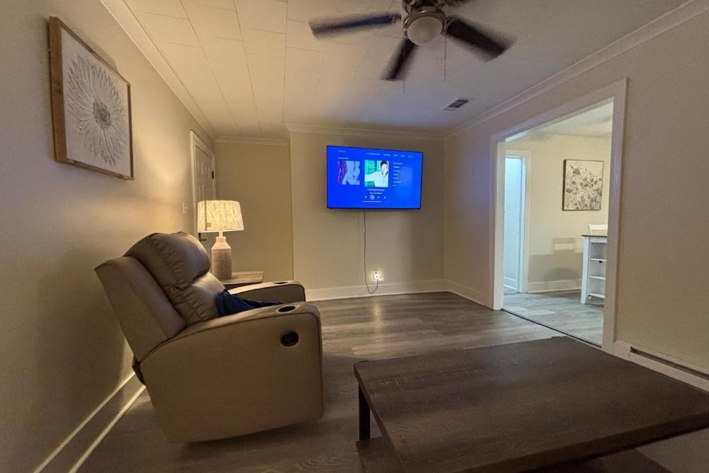 a living room with a chair and a flat screen tv at Close-to-Everything Midtown Cottage in Hattiesburg
