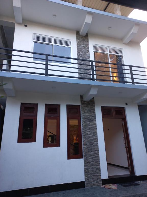 a white house with a balcony on top of it at Calm Stay in Badulla
