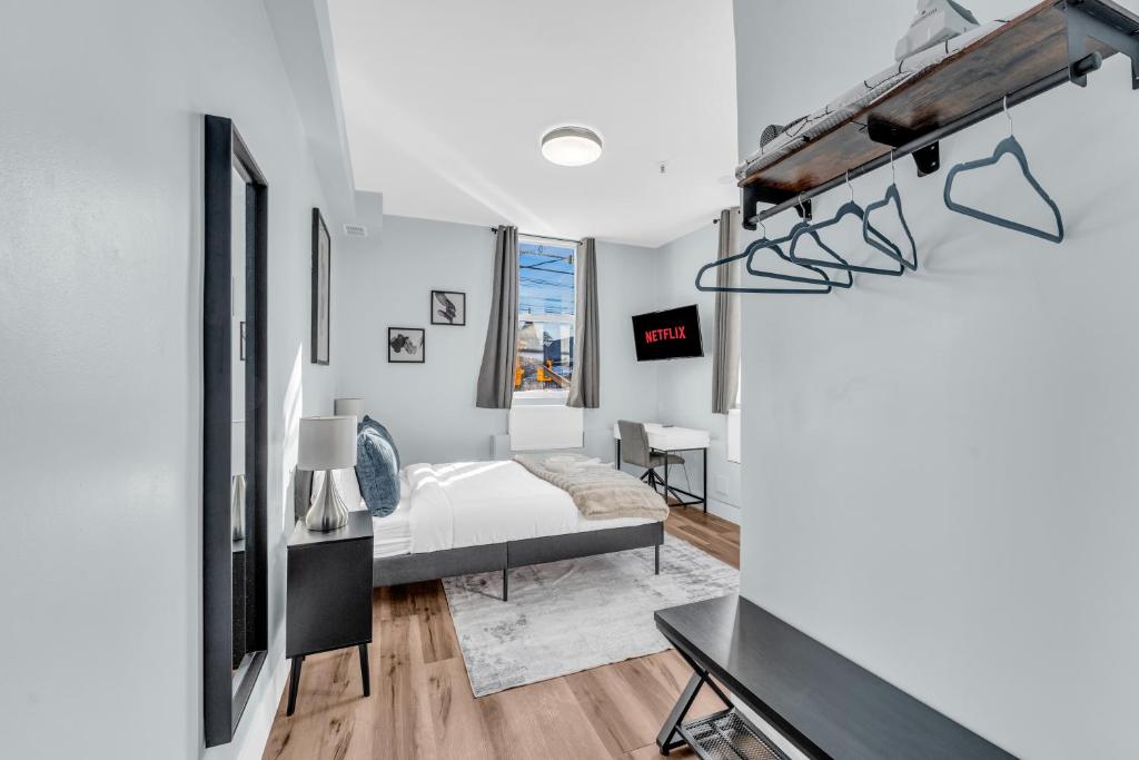 a white bedroom with a bed and a desk at Guestic Hotel at Queen West in Toronto