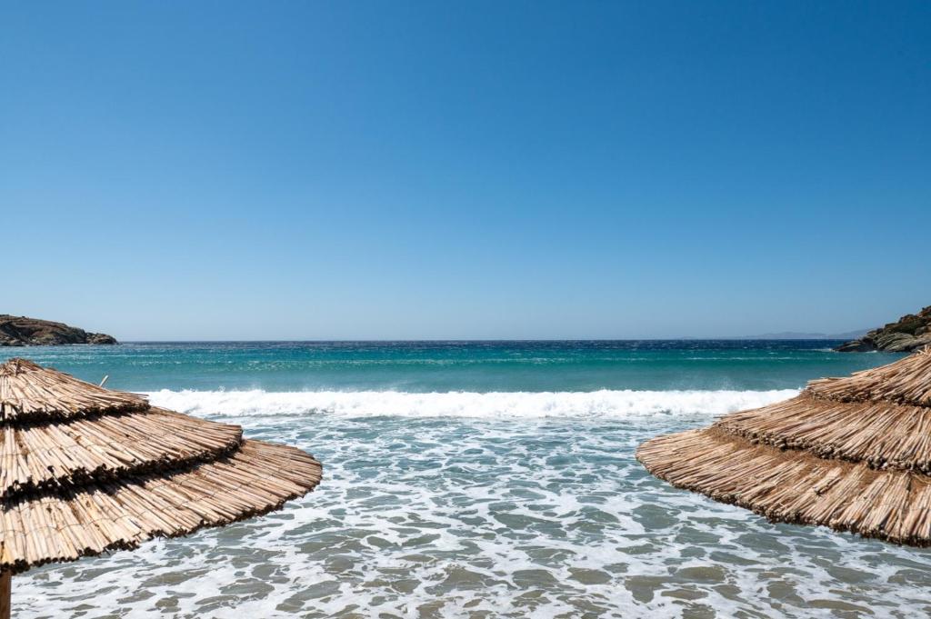 a group of straw umbrellas on a beach at The Goat House by Tinosstay in Kardhianí