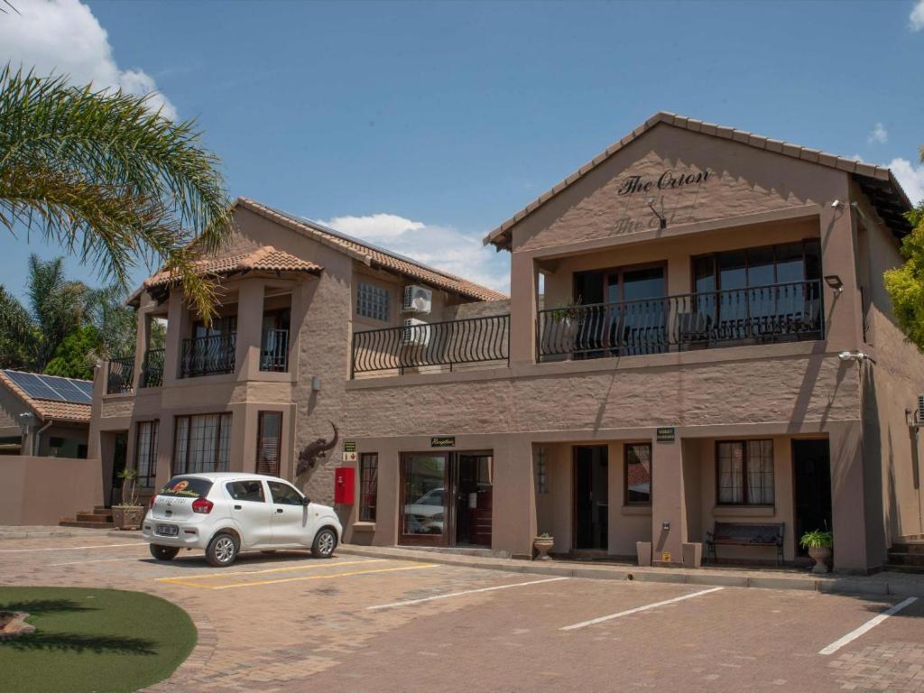 a white car parked in front of a building at The Orion Guesthouse in Middelburg