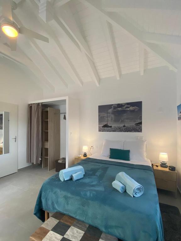 a white bedroom with a large bed with blue sheets at Résidence Fleur de Café - Petite Terre in Deshaies