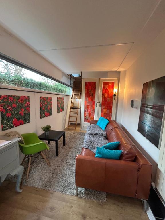 a living room with a brown leather couch and blue pillows at Huisje Vivaldi in Den Bosch