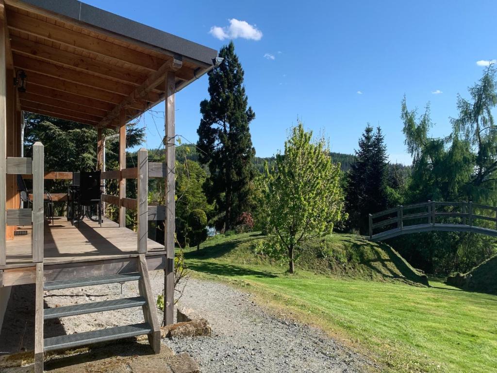 a wooden house with a bridge in the background at Familienurlaub mit Pool, Mittelndorf in Mittelndorf