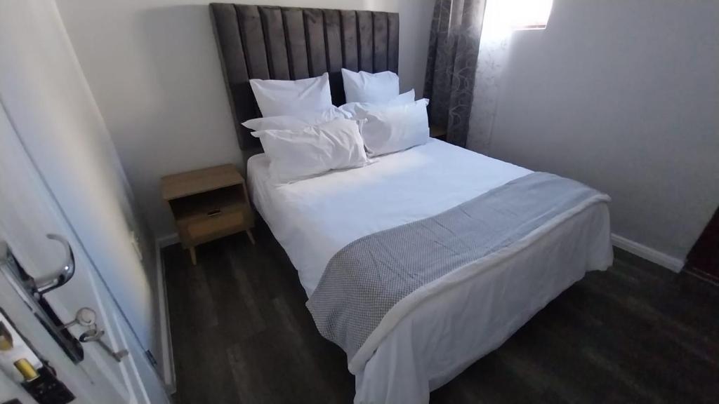 a bedroom with a bed with white sheets and pillows at B3 bnb House in Cape Town