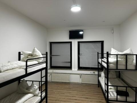 ein Zimmer mit drei Etagenbetten und zwei Fenstern in der Unterkunft Dottore Privatel in Hamburg