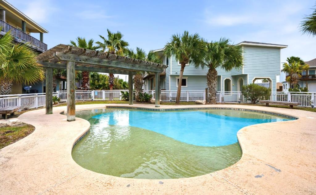 a swimming pool in front of a house with palm trees at Tranquil Turtle complete with Arcade plus Pool optional Golf Cart in Port Aransas