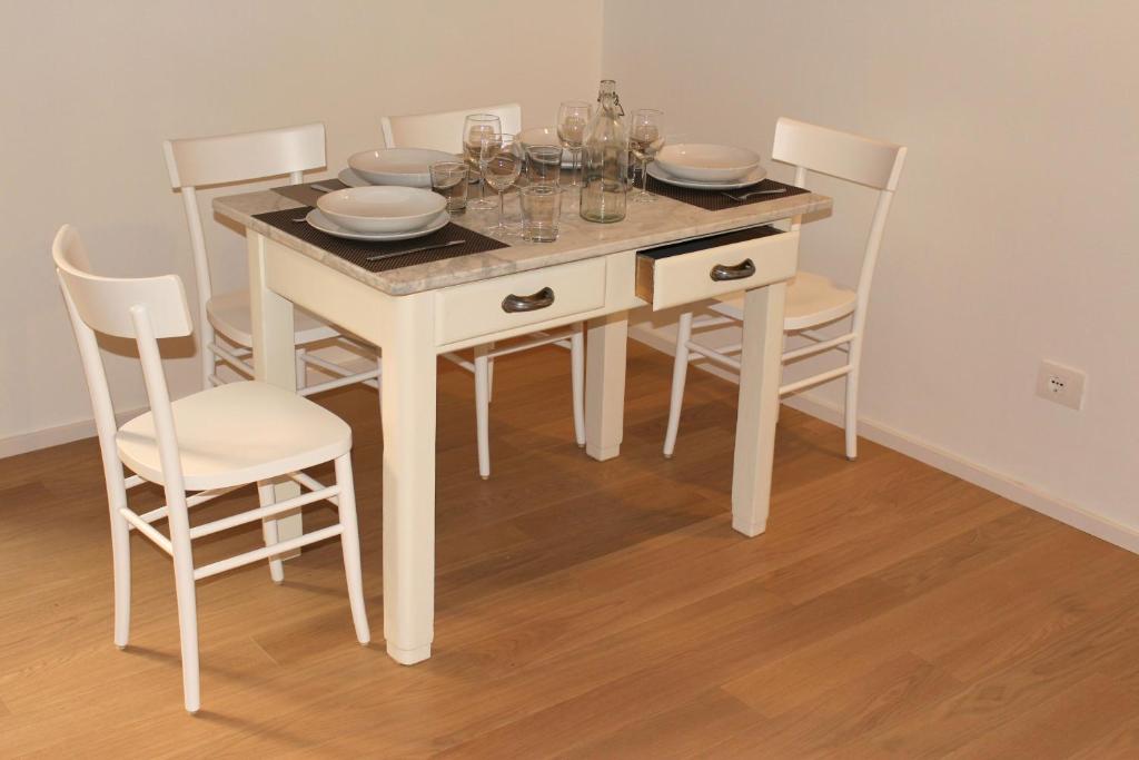 einen weißen Esstisch mit Stühlen, Tellern und Weingläsern in der Unterkunft Appartamento della Baia in Sestri Levante