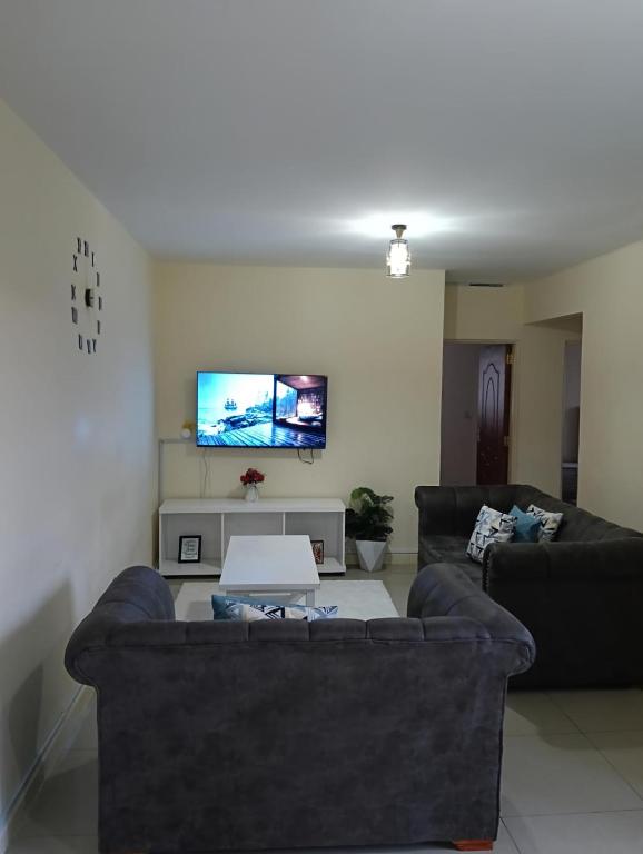 a living room with two couches and a tv at Chesum's suites in Eldoret