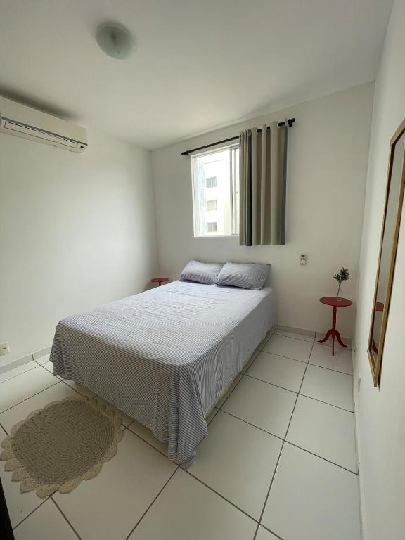 a white bedroom with a bed and a window at Apartamento confortável para sua estadia in Teresina