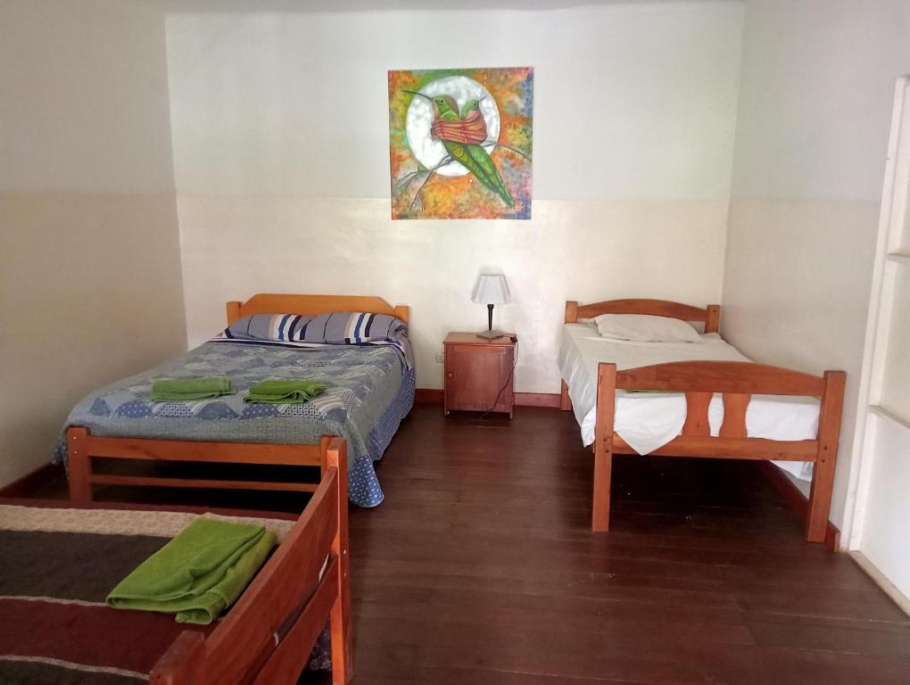 a bedroom with two beds and a painting on the wall at Casa Verde in Quillabamba