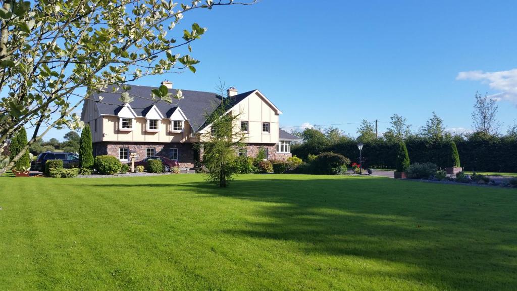 una casa grande con un gran césped verde en Cloghan Lodge, en Castleisland