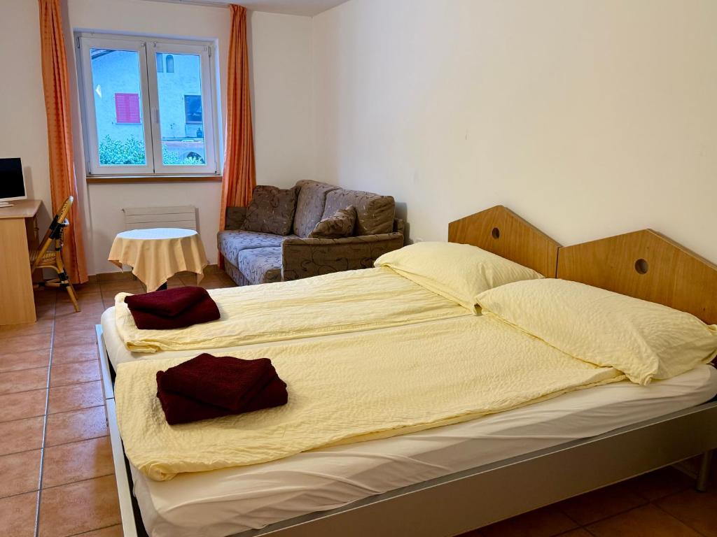 a bedroom with a large bed and a couch at Perla Valsole Hotel Ristorante in Acquarossa