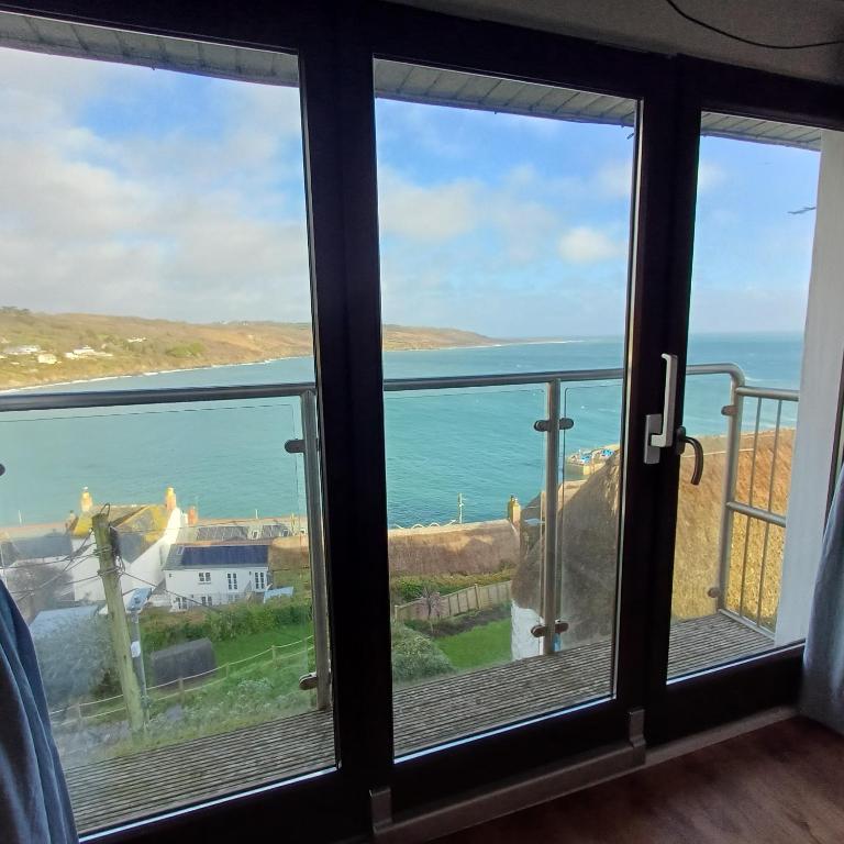 a view of the ocean from a room with windows at Harbour Views, Coverack in Helston