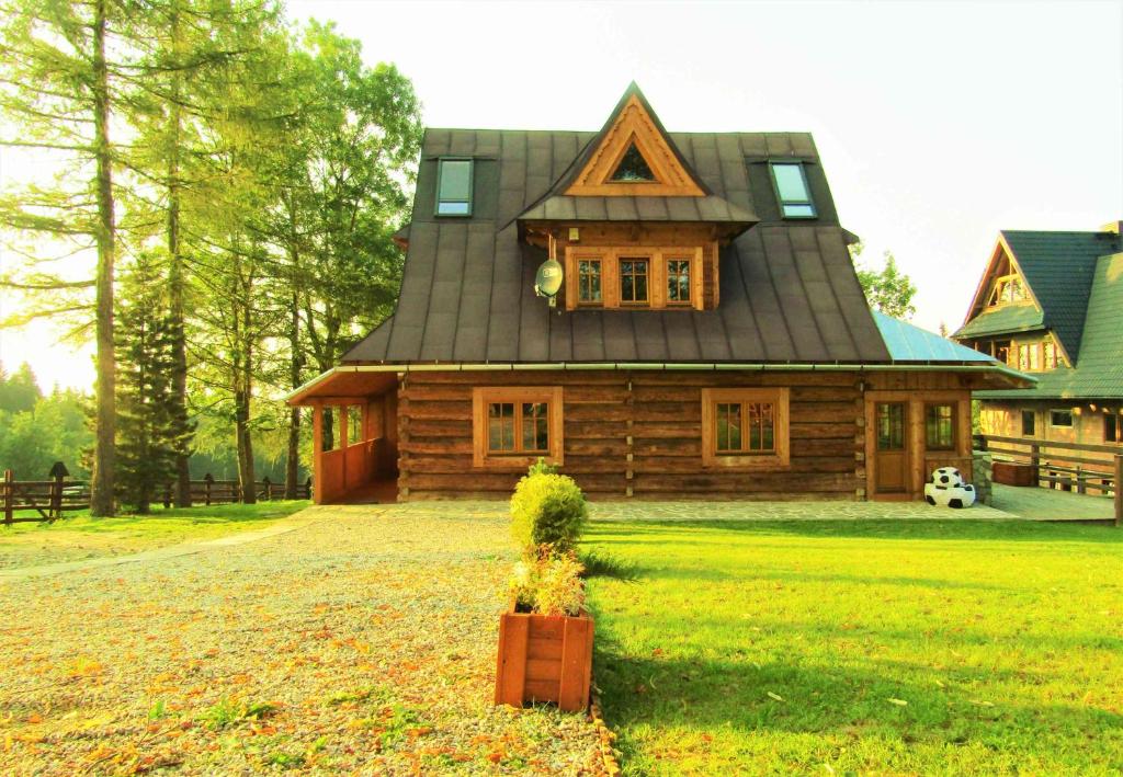 a wooden house with a roof on a yard at Pompelówka - chata na Głubałówce in Zakopane