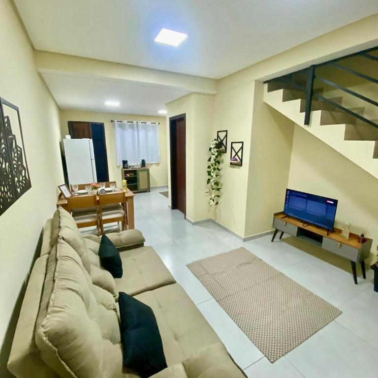 a living room with a couch and a table with a laptop at Casa completa com 2 quartos e garagem perto do aeroporto in Joinville