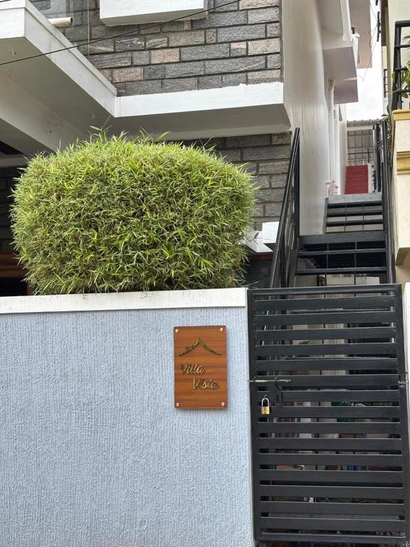 a sign on the side of a building with bushes at Villa Vista in Mysore