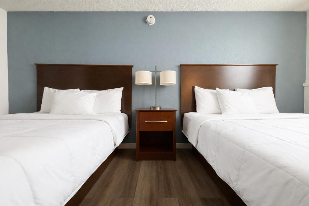 two beds in a hotel room with white sheets at Hotel 8 in Fergus Falls
