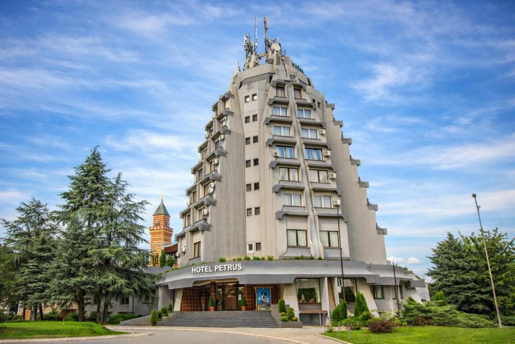 a tall white building with a sign on it at Hotel Petrus in Paraćin