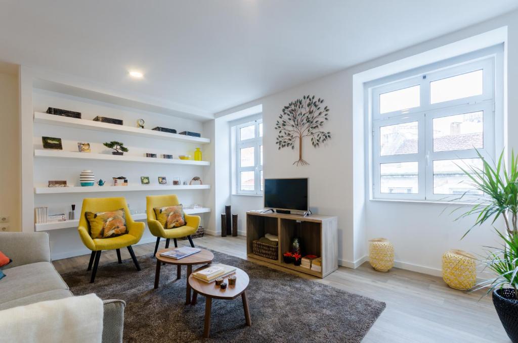 a living room with two yellow chairs and a tv at The Loghouse in Lisbon