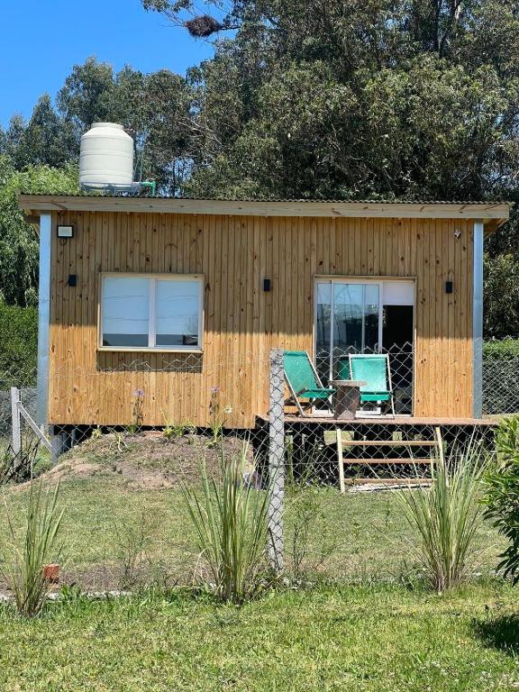 a tiny house with two chairs and a water tank at Casa Lobos en Chapadmalal in La Estafeta