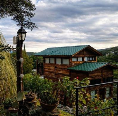 a wooden cabin with a green roof and a light pole at Cabaña La Triada Pileta Privada Grupo Cabaña La Triada in Río Ceballos