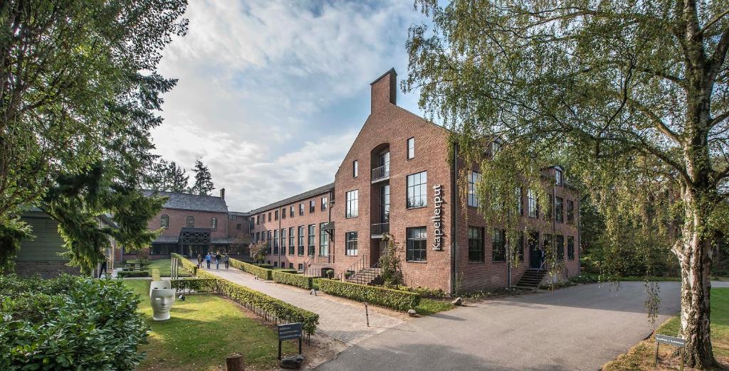 - un grand bâtiment en briques rouges avec une rue en face dans l'établissement Hotel Kapellerput Heeze-Eindhoven, à Heeze