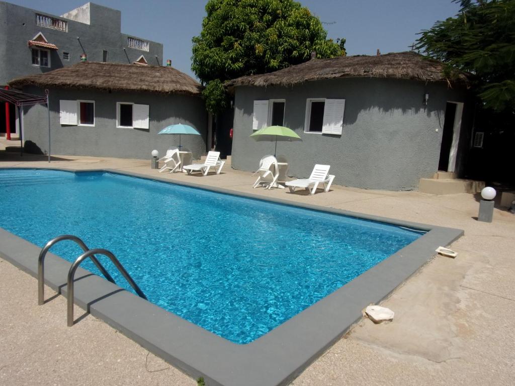 a pool with chairs and umbrellas next to a house at Melia Hotel in Saly Portudal