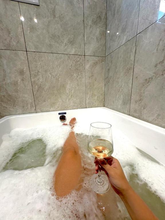 a person holding a glass of wine in a bath tub at Aires del Rio Apart in Villa de Soto
