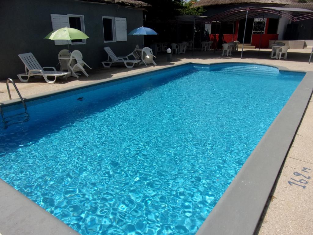 a pool with blue water and chairs and umbrellas at Melia Hotel in Saly Portudal