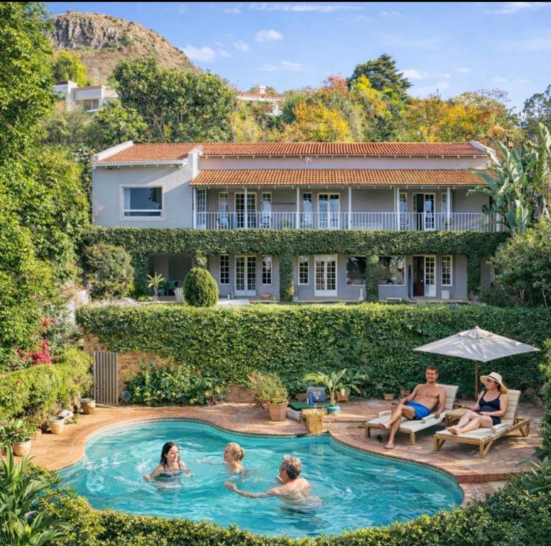 a group of people in a pool in front of a house at Ekhaya in Hartbeespoort