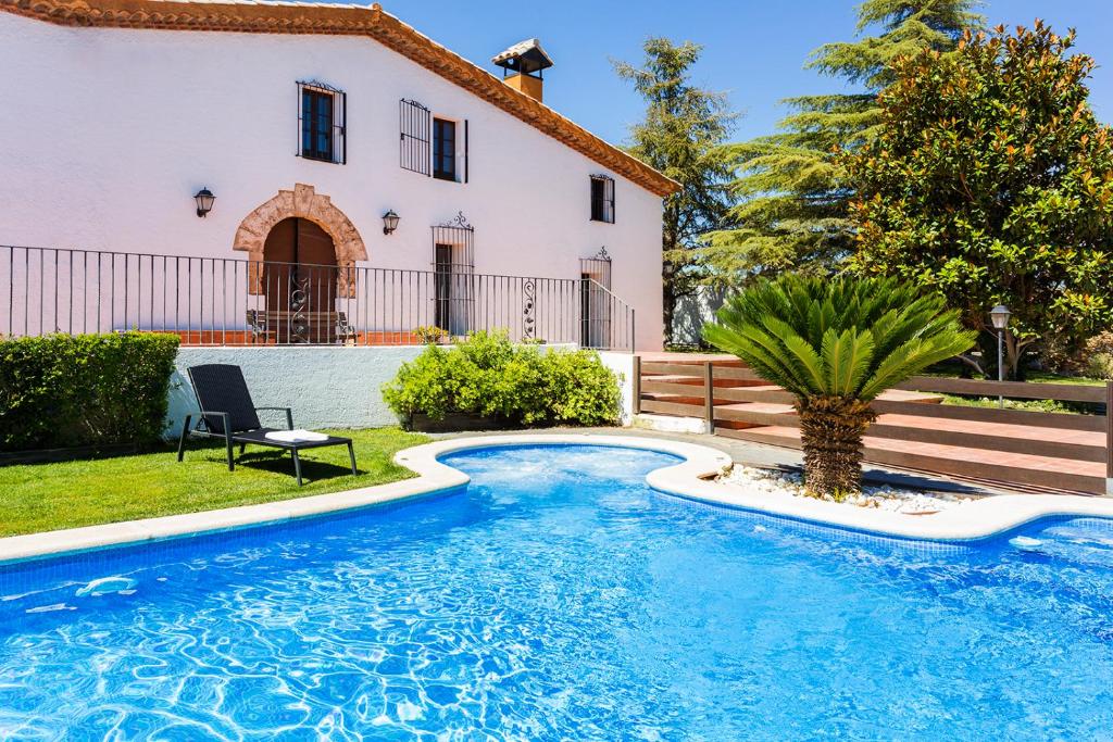 a large white swimming pool in front of a house at Masia Can Canyes & Spa in San Lorenzo de Hortóns