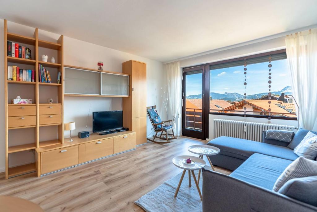 a living room with a blue couch and a large window at Bergerwachen in Bolsterlang