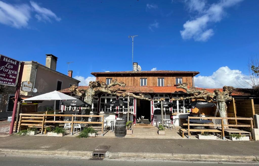 a building with tables and chairs in front of it at Auberge Les Mufliers - Hôtel Les Forges in Pontenx-les-Forges