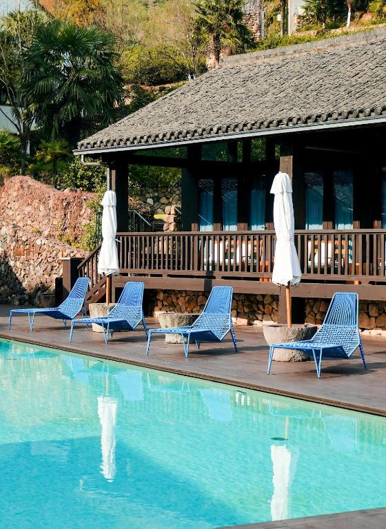 four blue chairs and umbrellas next to a swimming pool at Mocun Resort in Deqing