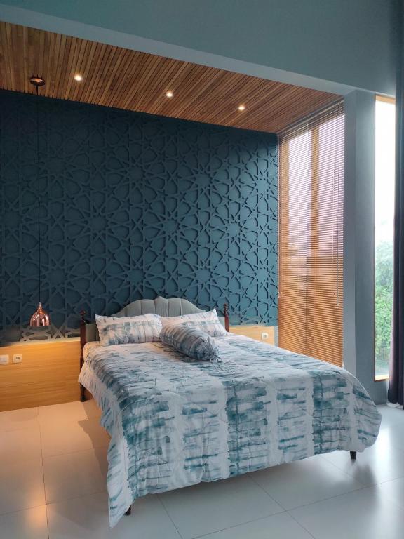 a bedroom with a bed with a blue wall at The Sawa Stay in Jarakan