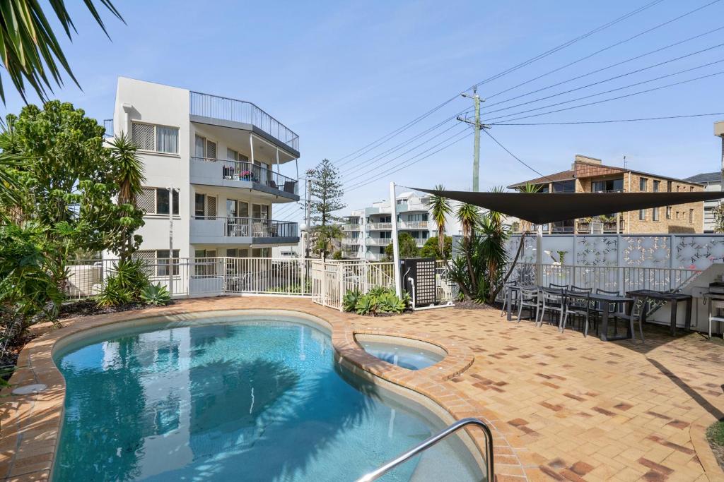 a swimming pool with a hammock and a building at Kings Way Apartments in Caloundra