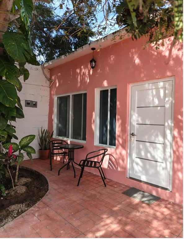 a pink house with a table and a white door at Casa Tamarindo in San Carlos
