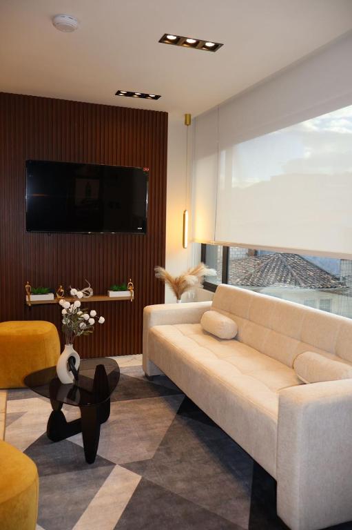 a living room with a couch and a tv at Ramon Luxury Suites in Gualaceo