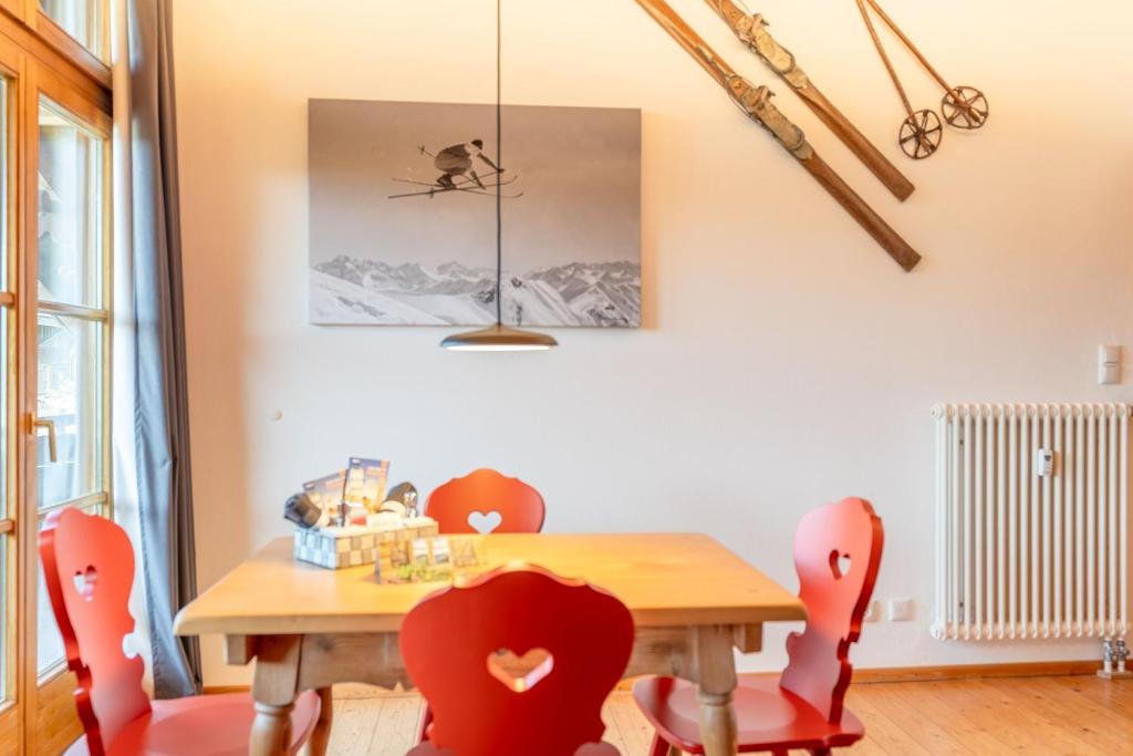a dining room with a wooden table and red chairs at Bergzitt in Ofterschwang