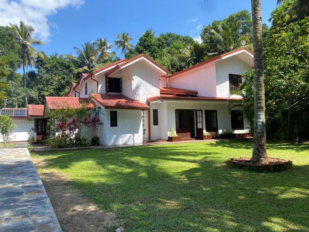 a white house with a tree in the yard at Kudaarala Heritage in Kengalla