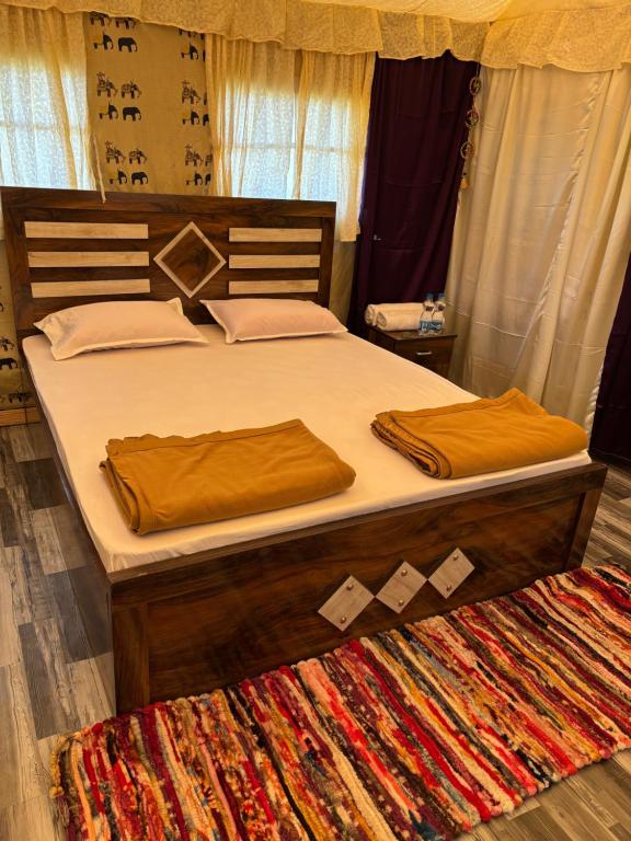 a bedroom with a bed with brown sheets and a rug at Aura Resort and Restaurant in Chikalthān